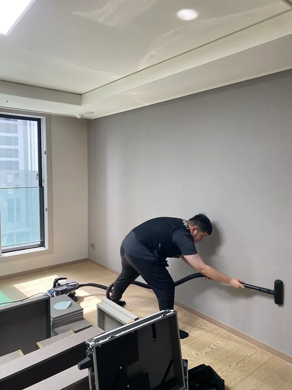 컬비 청소기로 벽면의 잔여 미세분진을 뽑아내는 작업자
