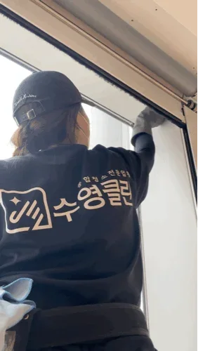 수영클린 작업복을 입고 창틀을 닦는 작업자