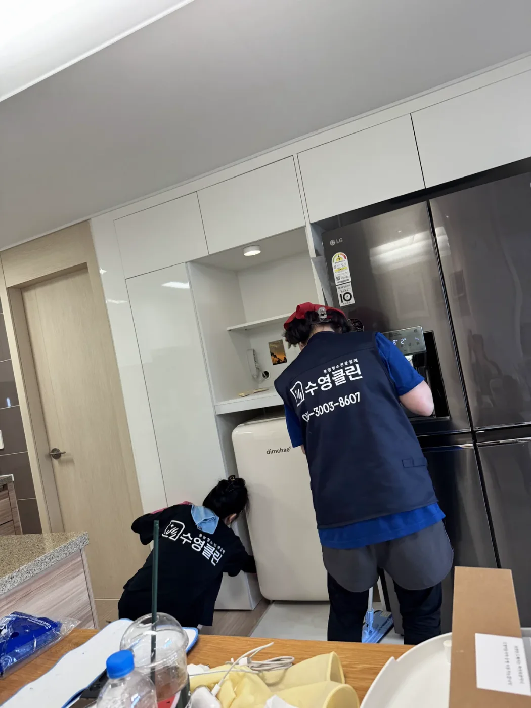 냉장고 옆 주방 바닥을 청소하는 작업자들