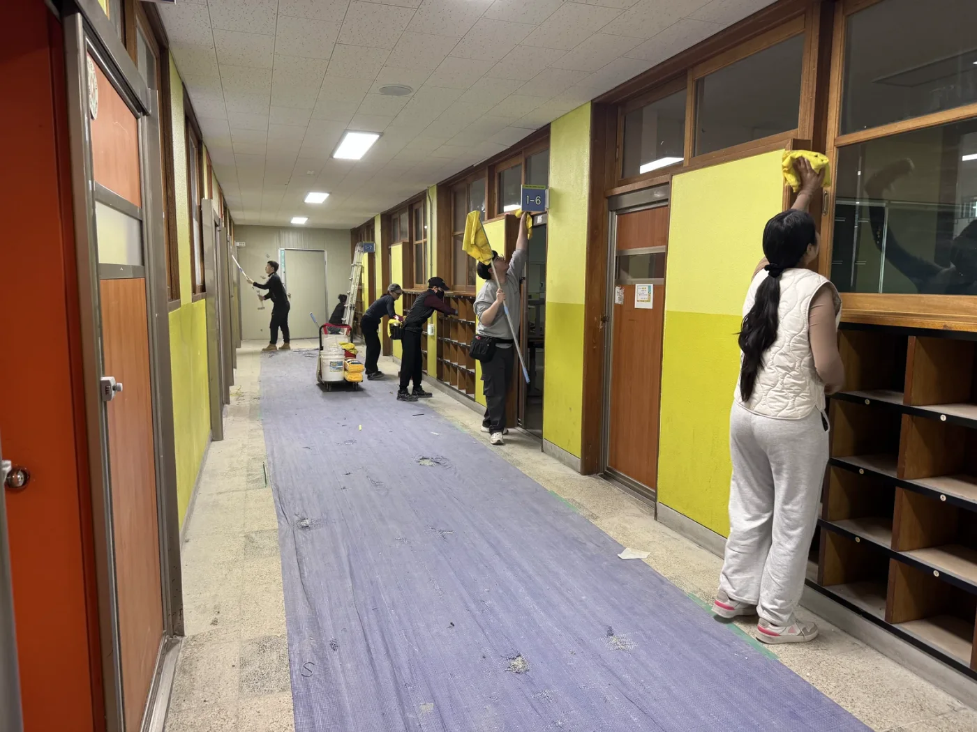 복도 바닥에 양생재를 깔고 청소하는 현장