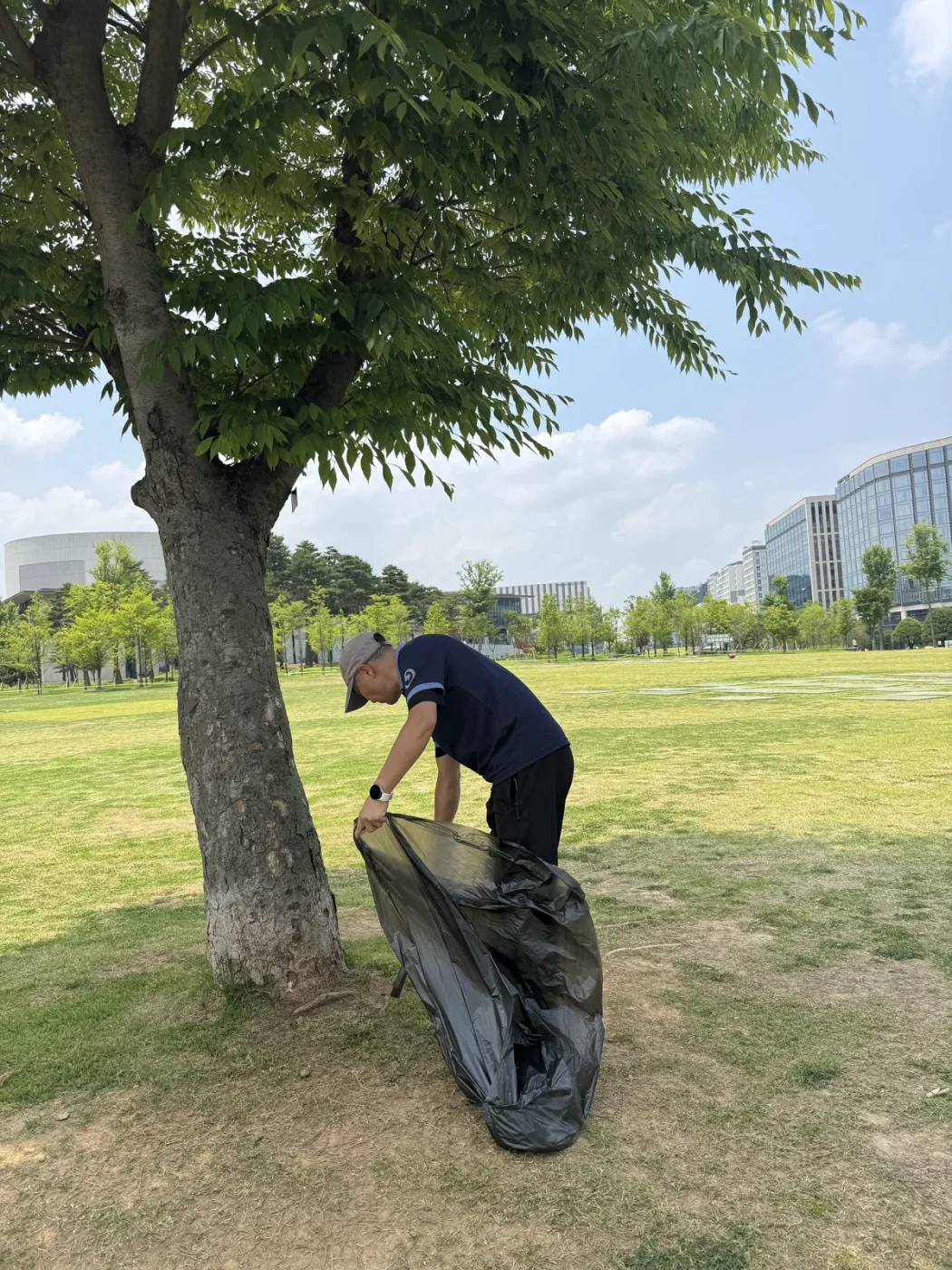 나무 아래 쓰레기 봉투를 정리하는 작업자