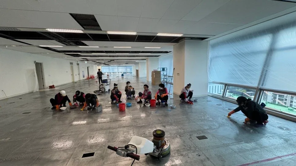 여러 작업자가 상업 공간 바닥을 손으로 닦는 모습